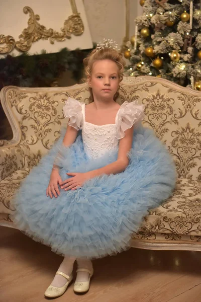 Prenses mavi zarif elbise ile beyaz bir koltukta oturur — Stok fotoğraf