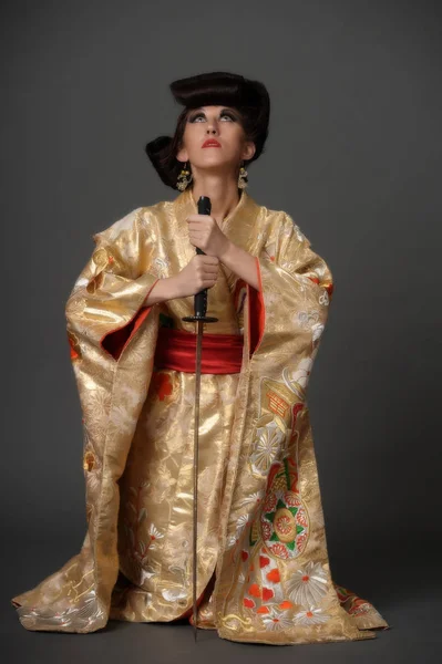 Uma mulher em kimano dourado — Fotografia de Stock