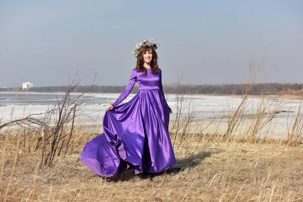 Fliederfarbenes Kleid mit einem Blumenkranz auf dem Kopf auf die Natur — Stockfoto