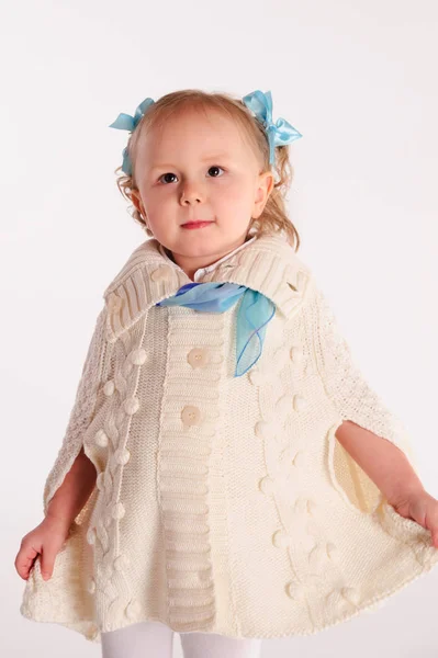 Petite fille dans un emballage tricoté en laine poncho sur un dos blanc — Photo