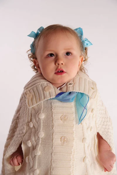 Menina em um agasalho de malha lanoso - poncho em um backgro branco — Fotografia de Stock