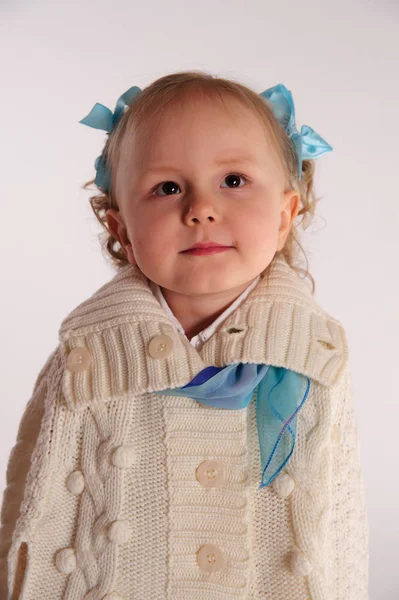 Bambina in un involucro lavorato a maglia di lana - poncho su uno sfondo bianco — Foto Stock