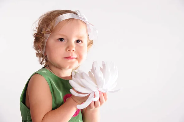 Chica en el estudio se sienta en un vestido verde con una gran flor blanca — Foto de Stock