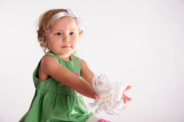 Girl in the studio sits in a green dress with a big white flower — Stock Photo, Image