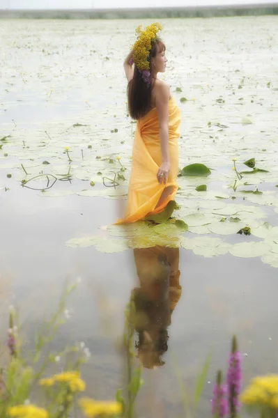 Брюнетка девушка в желтом платье с венком цветов на ней — стоковое фото