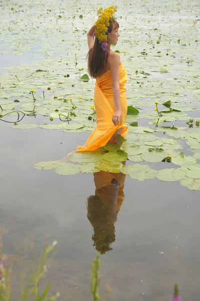 Chica morena en un vestido amarillo con una corona de flores en su —  Fotos de Stock