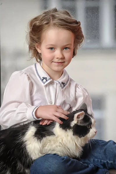 Linda chica con un gato en sus brazos se sienta — Foto de Stock