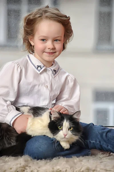 Roztomilá dívka s kočkou v náručí sedí — Stock fotografie