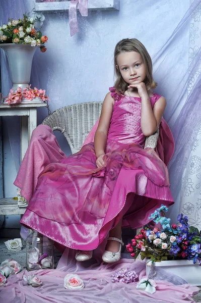 Cute girl in a pink dress sits on a chair — Stock Photo, Image