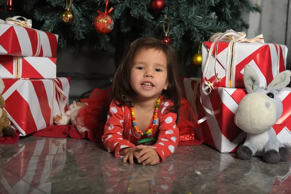 Little girl in a dress near the Christmas tree lies on the floor — ストック写真