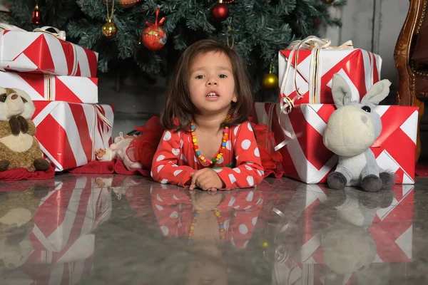 在圣诞树旁穿着连衣裙的小女孩躺在地板上 — 图库照片