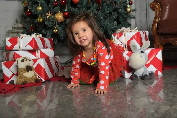 Petite fille dans une robe près du sapin de Noël se trouve sur le sol — Photo