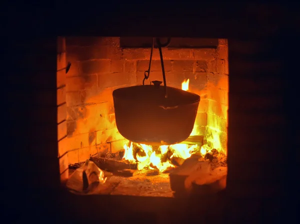 A comida cozinha-se em uma caldeira em uma lareira — Fotografia de Stock