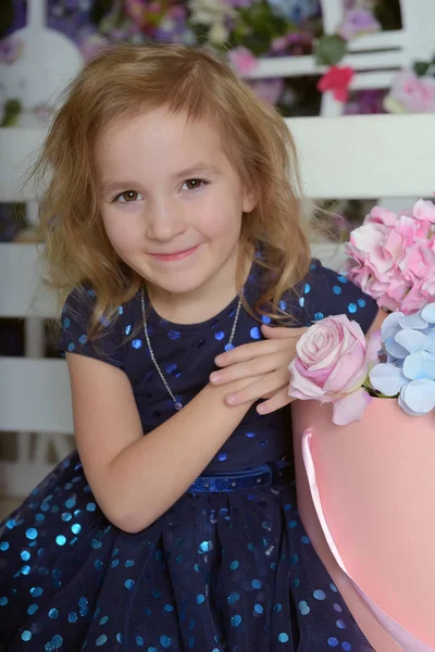 Lány kék ruhában csillogó, boldog gyermek egy mosollyal ül — Stock Fotó
