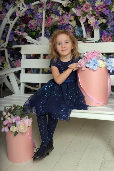 Girl in blue dress with sparkles, happy child with a smile sits — Stockfoto