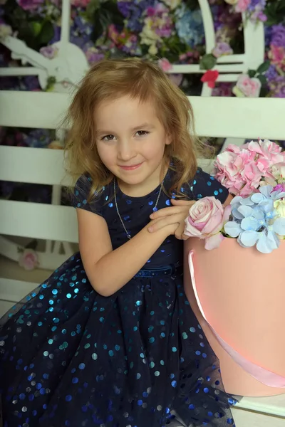 Menina em vestido azul com brilhos, criança feliz com um sorriso senta-se — Fotografia de Stock