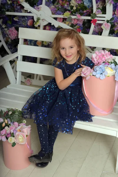 Girl in blue dress with sparkles, happy child with a smile sits — Stockfoto