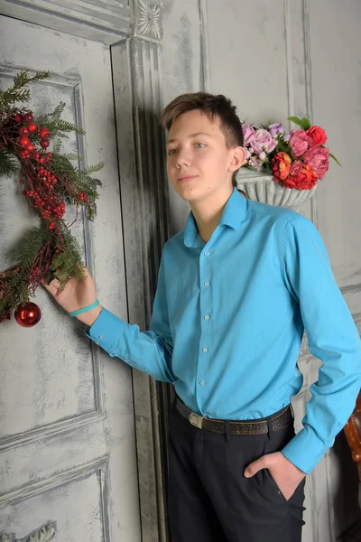 Adolescente menino em camisa azul no Natal na porta com o Natal — Fotografia de Stock