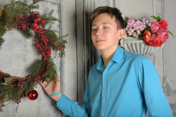 Adolescente ragazzo in camicia blu a Natale alla porta con il Natale — Foto Stock