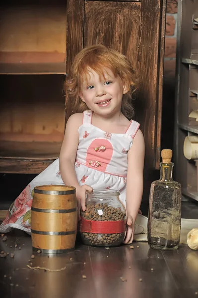 红头发的女孩坐在老式厨房里玩耍 — 图库照片