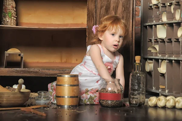 红头发的女孩坐在老式厨房里玩耍 — 图库照片