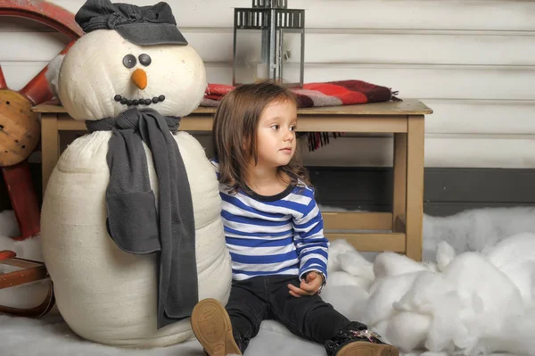 Chica con un muñeco de nieve de juguete . —  Fotos de Stock