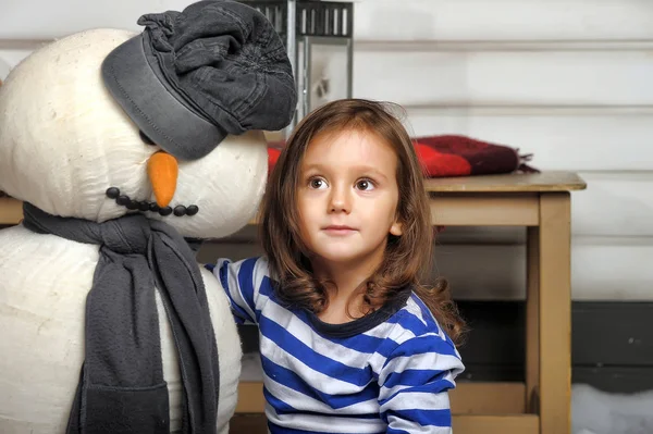 Chica con un muñeco de nieve de juguete . —  Fotos de Stock