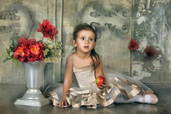 Een mooi meisje, een kind in een mooie jurk en een vaas bloemen — Stockfoto