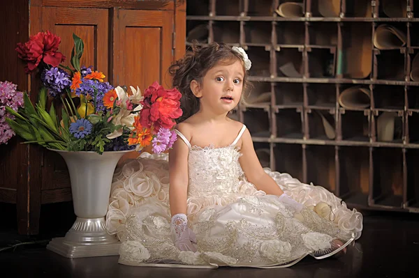 Uma menina bonita, uma criança em um vestido bonito e um vaso de flores — Fotografia de Stock