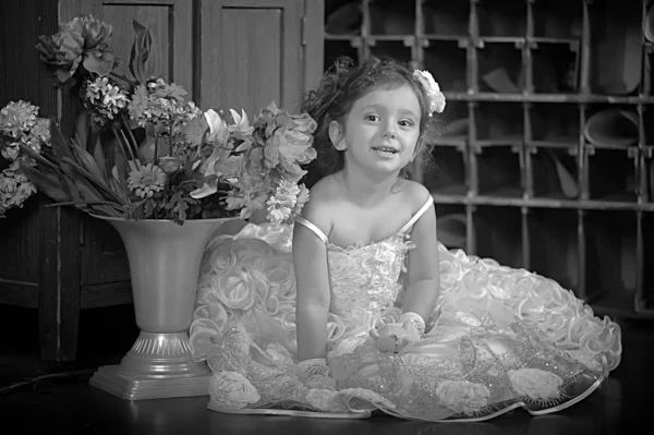 Uma menina bonita, uma criança em um vestido bonito e um vaso de flores — Fotografia de Stock