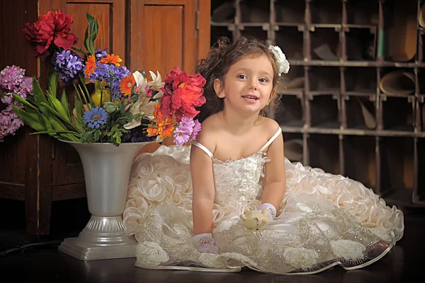 Uma menina bonita, uma criança em um vestido bonito e um vaso de flores — Fotografia de Stock