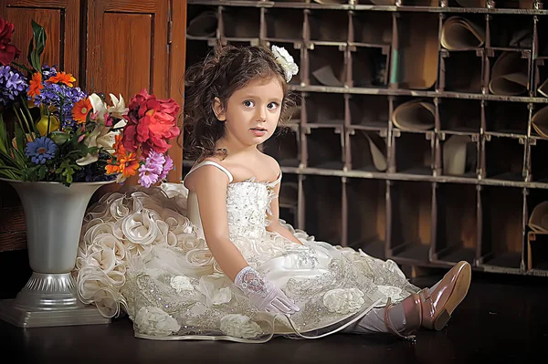 Una chica hermosa, un niño con un bonito vestido y un jarrón de flores — Foto de Stock