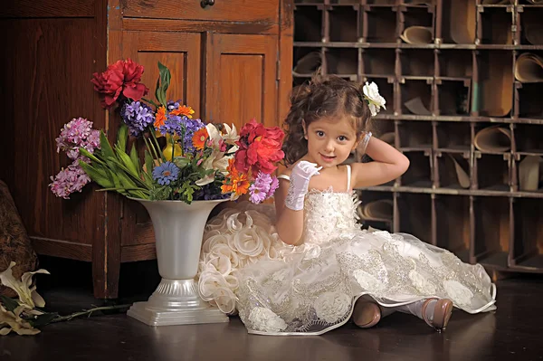 Una chica hermosa, un niño con un bonito vestido y un jarrón de flores — Foto de Stock