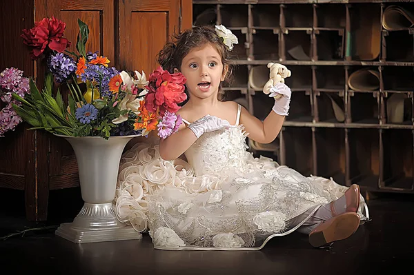 Una chica hermosa, un niño con un bonito vestido y un jarrón de flores — Foto de Stock