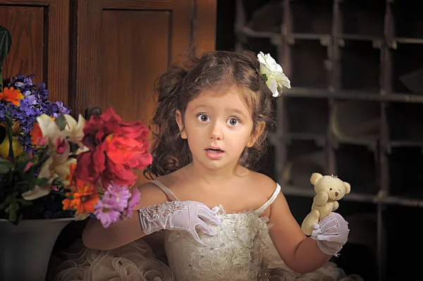 Una chica hermosa, un niño con un bonito vestido y un jarrón de flores — Foto de Stock