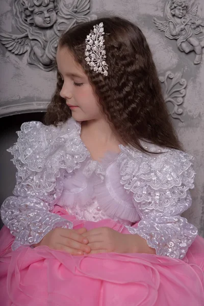 Schattig meisje prinses met krullend haar in een wit met roze jurk — Stockfoto
