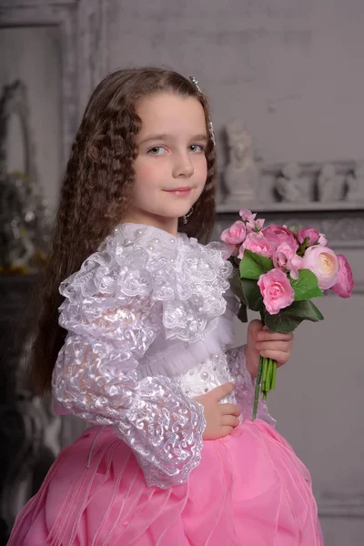 Jolie fille princesse avec des cheveux bouclés et des fleurs dans ses bras, brun — Photo