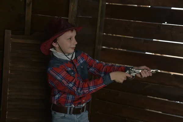 Elinde silahla kovboy şapkalı ekose gömlekli bir çocuk. — Stok fotoğraf