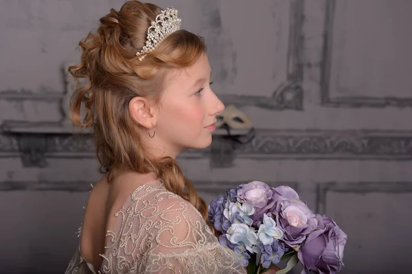 Uma menina em um vestido branco inteligente com um diadema em seu cabelo e um bo — Fotografia de Stock