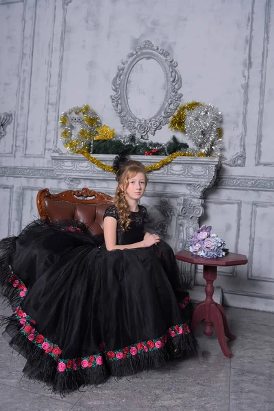 Chica en un vestido negro inteligente en una silla — Foto de Stock