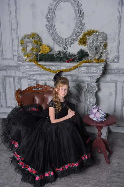 Chica en un vestido negro inteligente en una silla — Foto de Stock