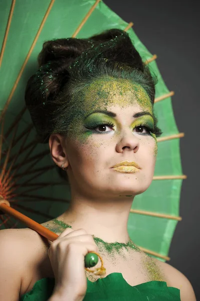 Dziewczyna w zieleni ze stylową stylizacją włosów i kreatywny makijaż dowcip — Zdjęcie stockowe