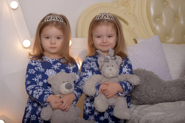 Mavi elbiseli küçük ikiz kızlar ellerinde oyuncak ayılarla — Stok fotoğraf