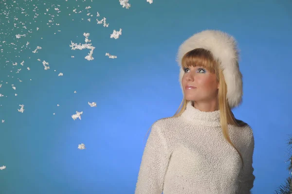 Beautiful long-haired blonde in the studio in a white fur hat in — Stok fotoğraf