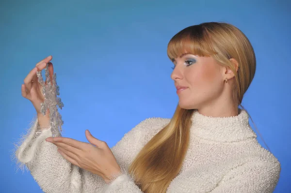 Long-haired blonde in the studio on a blue background with a sno — Stock Photo, Image