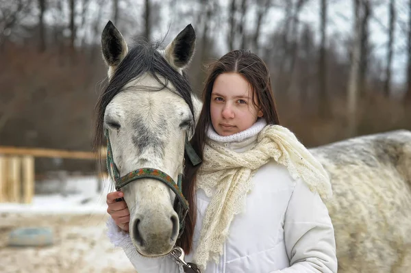 Dziewczyna w białym płaszczu w zimie z koniem — Zdjęcie stockowe