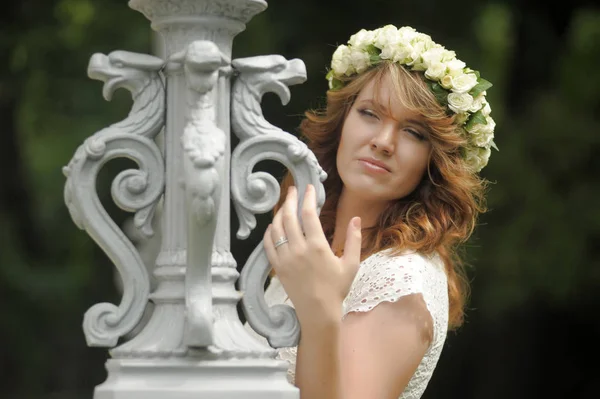 Mooie jonge brunette in een krans van witte bloemen — Stockfoto