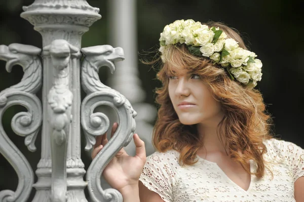 Bela jovem morena em uma grinalda de flores brancas — Fotografia de Stock