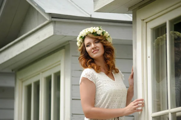 Beautiful young brunette in a wreath of white flowers — Stock Photo, Image