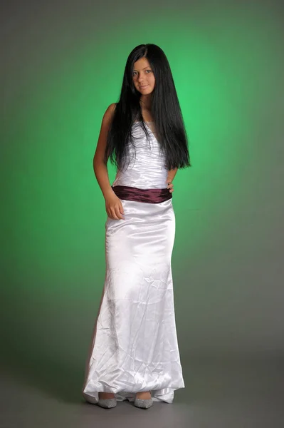 Μελαχρινή κοπέλα σε ένα μακρύ λευκό φόρεμα στο στούντιο σε ένα πράσινο bac — Φωτογραφία Αρχείου